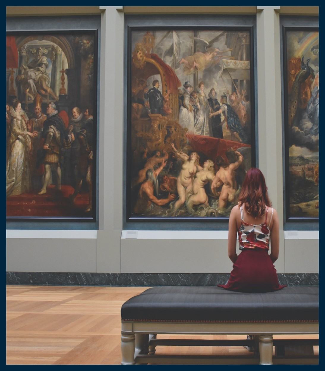 Woman sitting in a museum, looking at 18th century paintings.